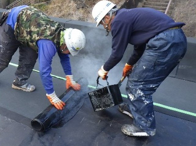 三財発電所屋根防水工事でアスファルトを流し込む作業
