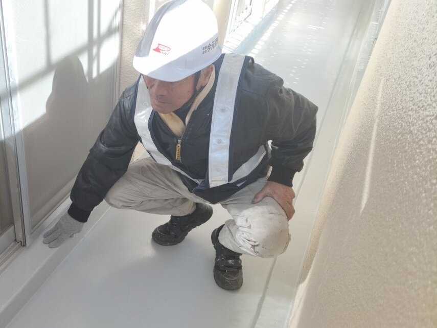 塗装を終えたベランダの床を確かめる職人