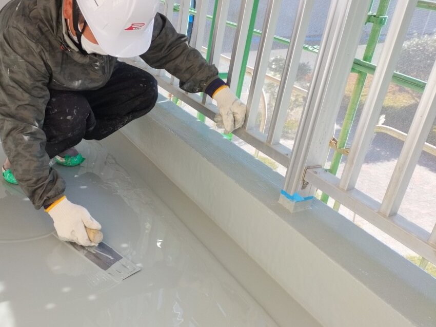 ベランダの床に防水材を塗る職人